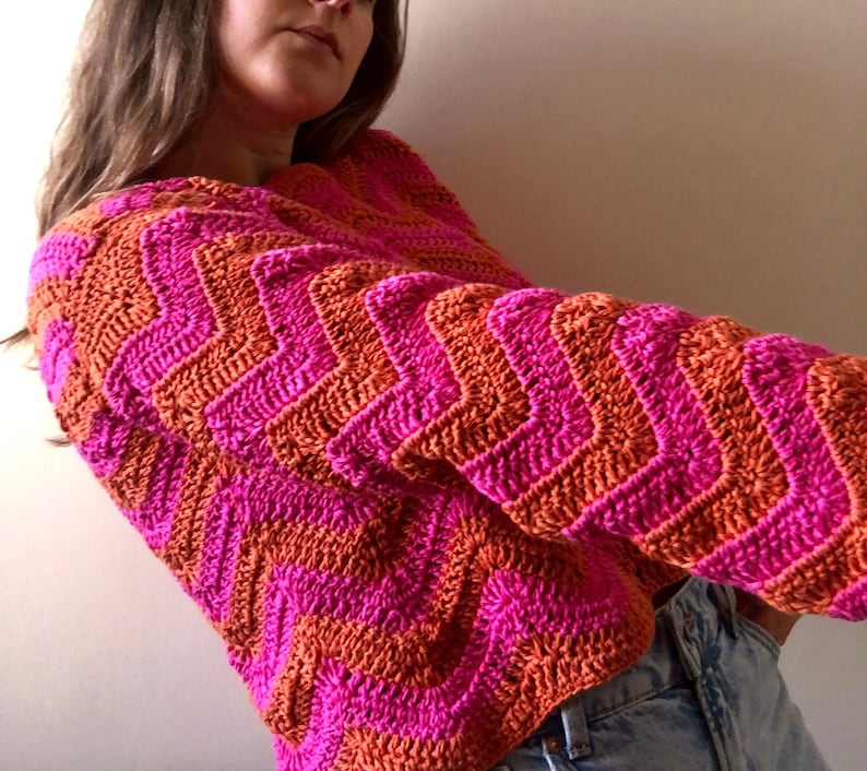 May include: A pink and orange crochet sweater with a chevron pattern.