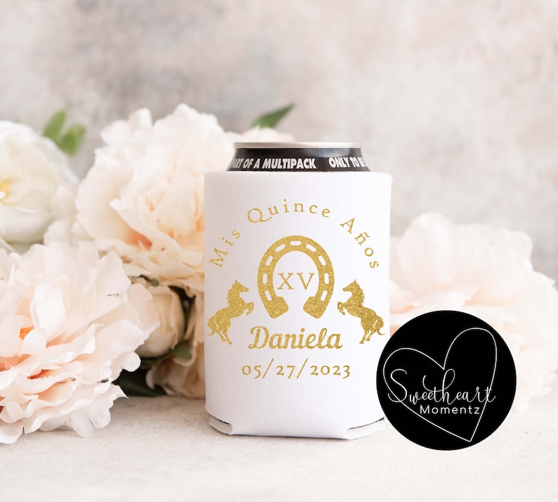 May include: White can cooler with gold text and graphics for a quincea&ntilde;era. The design includes a horseshoe, horses, the name "Daniela", and the date 05/27/2023. The words "Mis Quince A&ntilde;os" are also present.
