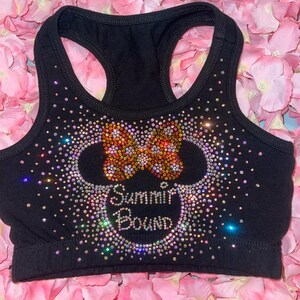 May include: Black sports bra with a racerback design, embellished with sparkling rhinestones. The design features a bow and the words "Summit Bound" in a decorative font, creating a glamorous athletic top.