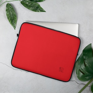 Puede incluir: Funda para portátil de color rojo con una cremallera negra y un logotipo "R" negro. La funda está hecha de un material suave y acolchado y está diseñada para proteger tu portátil de arañazos y golpes.