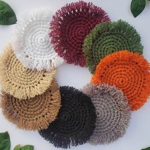 May include: Set of eight crocheted coasters with fringe. The coasters are in various colors, including white, beige, brown, black, gray, green, orange, and burgundy.