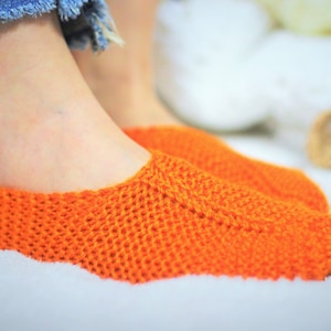 Puede incluir: Un par de calcetines de pantuflas de punto naranja. Los calcetines están hechos de un material suave y cómodo y son perfectos para mantener los pies calientes.