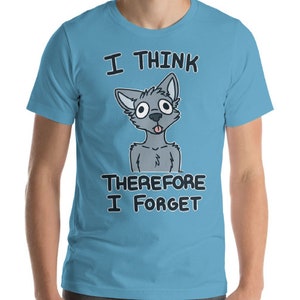 Puede incluir: Una camiseta azul claro con un lobo gris de dibujos animados con la lengua fuera. El texto "Pienso, luego olvido" est&aacute; impreso en la camiseta.