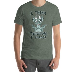 Puede incluir: Una camiseta verde con un drag&oacute;n de dibujos animados y el texto "Pienso, luego olvido".