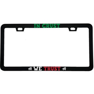 May include: Black license plate frame with the text "IN CRUST" in green at the top and "WE TRUST" in red at the bottom. Pizza slice graphics are on either side of the text. The frame has a rectangular shape.