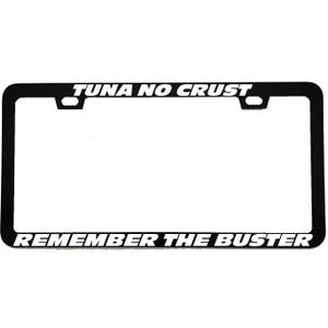 May include: A rectangular black license plate frame featuring white text. The top portion displays the words TUNA NO CRUST, while the bottom portion displays the words REMEMBER THE BUSTER. The frame includes two mounting holes at the top.