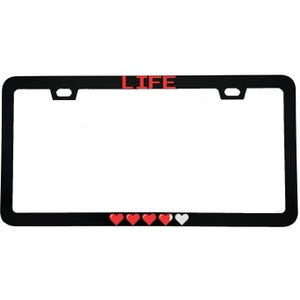 May include: Black license plate frame with the word "LIFE" in red block letters at the top. Four red hearts and one white heart are at the bottom. The frame is rectangular with rounded corners.