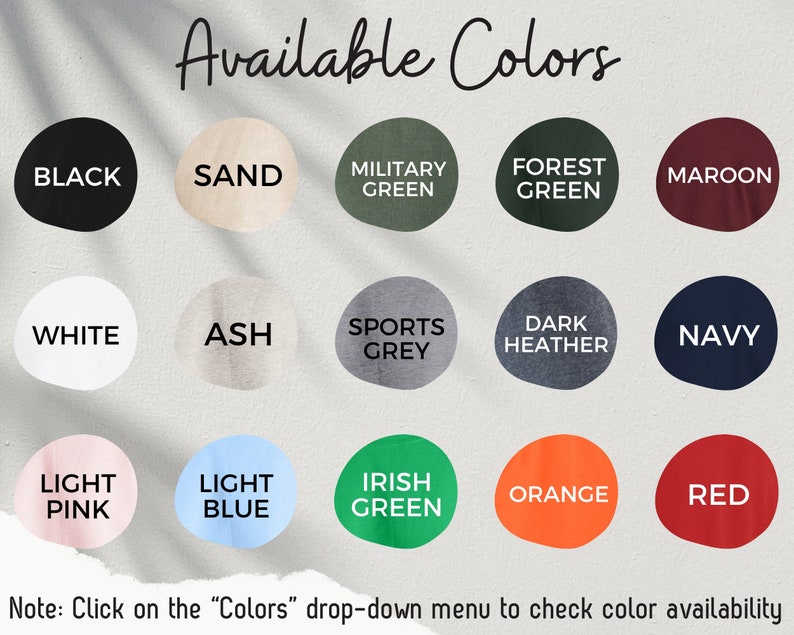 May include: A chart showing 18 different color options for a product. The colors include black, white, sand, ash, light pink, light blue, military green, forest green, sports grey, dark heather, navy, irish green, orange, and red. The text "Available Colors" is at the top of the chart.