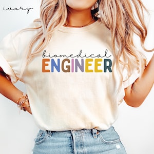 May include: A white t-shirt with the text "biomedical ENGINEER" in colorful letters. The letters are in different colors, including orange, yellow, brown, purple, and blue.