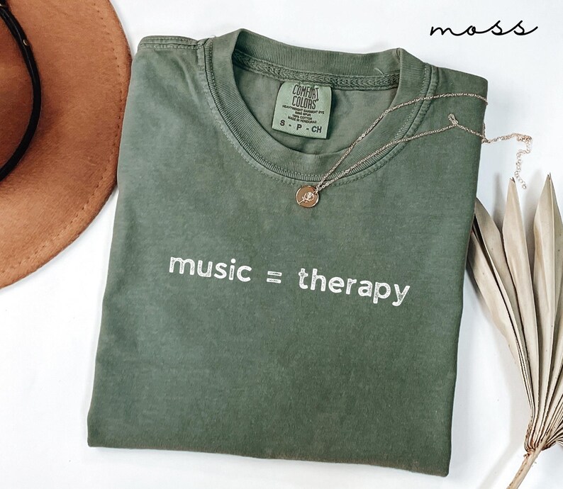May include: A green t-shirt with the text "music = therapy" in white embroidery. The shirt is made by Comfort Colors and is a size S-P-CH.