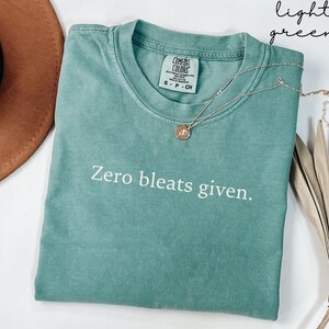 May include: A light green t-shirt with the text "Zero bleats given." printed in white. The shirt is made of a soft, comfortable fabric.
