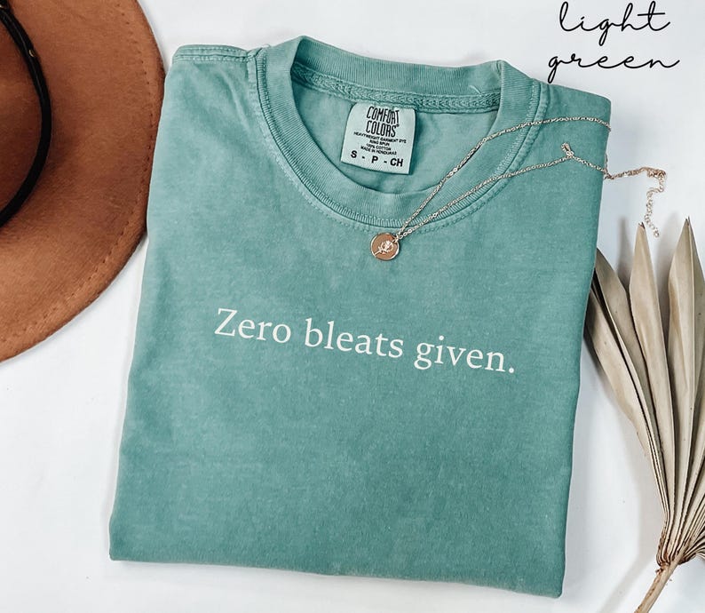 May include: A light green t-shirt with the text "Zero bleats given." printed in white. The shirt is made of a soft, comfortable fabric.