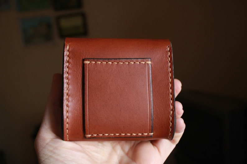 May include: A brown leather wallet with a stitched flap and a smaller pocket on the front.