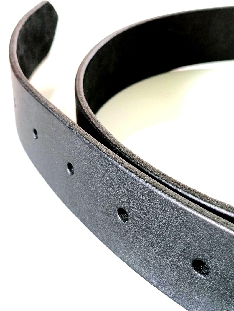 K&ouml;nnte beinhalten: Nahaufnahme eines schwarzen Lederg&uuml;rtels mit mehreren gleichm&auml;&szlig;ig verteilten L&ouml;chern. Der G&uuml;rtel ist gebogen und zeigt seine Dicke und Textur. Der Hintergrund ist wei&szlig; und hebt die Details des G&uuml;rtels hervor.