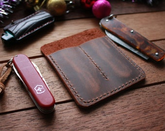 May include: A brown leather knife carrying case with two slots for knives. The case is stitched with brown thread and has a distressed look. 