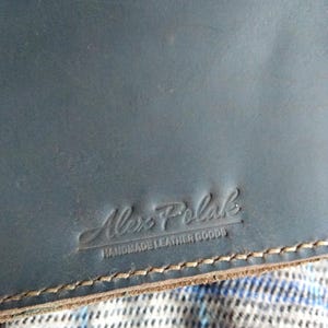 Pu&ograve; includere: Un taccuino in pelle blu scuro con il testo "Alex Polak Handmade Leather Goods" in rilievo sulla copertina.