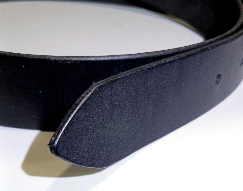 May include: Close-up of a black leather belt. The belt is made of a smooth, dark material and has a classic design. The buckle is not visible in the image.