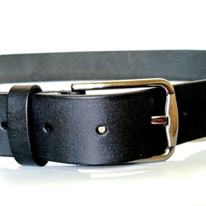 K&ouml;nnte beinhalten: Nahaufnahme eines schwarzen Lederg&uuml;rtels mit silberner Schnalle. Der G&uuml;rtel hat ein klassisches Design mit rechteckiger Schnalle und einer einzelnen G&uuml;rtelschlaufe. Das Leder wirkt glatt und ist f&uuml;r den t&auml;glichen Gebrauch geeignet.