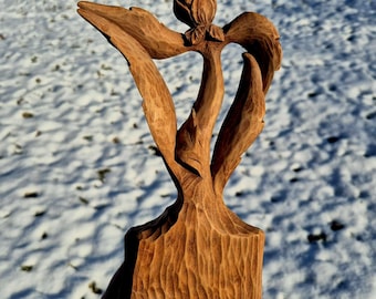 Op de afbeelding: Een houten sculptuur van een gestileerde bloem met een enkele bloei en bladeren. Het beeldhouwwerk is gesneden uit lichtbruin hout en heeft een natuurlijke, rustieke afwerking.