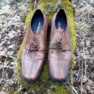 K&ouml;nnte beinhalten: Ein Paar braune Lederschn&uuml;rschuhe mit dem Wort "IKON" auf der Innenseite jedes Schuhs.