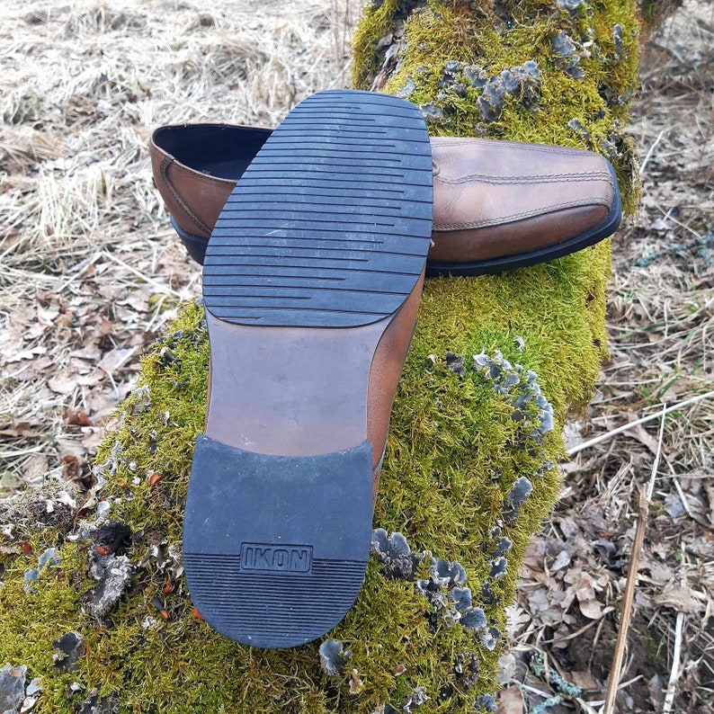 K&ouml;nnte beinhalten: Ein brauner Lederschuh mit einer schwarzen Gummisohle. Die Sohle tr&auml;gt den Schriftzug "IKON".