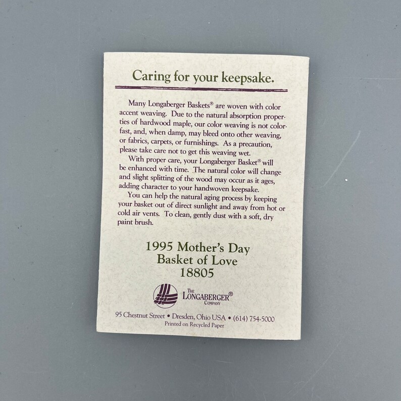 May include: A white card with brown text detailing how to care for a Longaberger Basket. The card includes the text "Caring for your keepsake." and "1995 Mother's Day Basket of Love 18805". The card also includes the Longaberger logo and contact information.