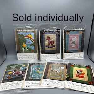 May include: A collection of eight vintage quilt patterns featuring various themes, including a rocking horse, a sunbonnet, and a lamb pie. Each pattern is packaged in a clear plastic sleeve and includes the text "The Gingham Goose" and "VIP".