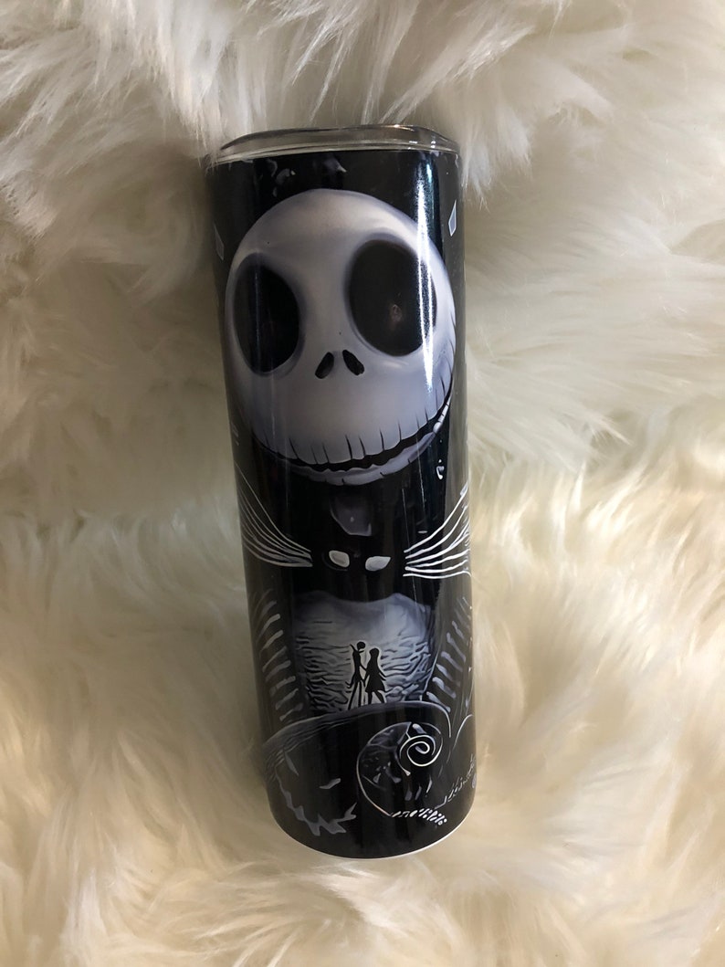 K&ouml;nnte beinhalten: Ein schwarzer und wei&szlig;er Becher mit einem Motiv von Jack Skellington aus Nightmare Before Christmas. Das Motiv zeigt Jacks Gesicht und eine Szene aus dem Film.