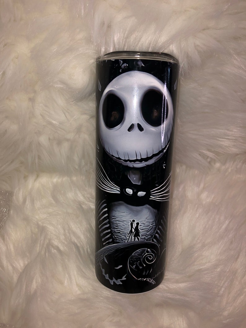 K&ouml;nnte beinhalten: Ein schwarz-wei&szlig;er Edelstahlbecher mit einem Motiv von Jack Skellington aus dem Film Nightmare Before Christmas. Das Motiv zeigt Jack Skellingtons Gesicht und K&ouml;rper, im Hintergrund eine Silhouette von Jack und Sally.