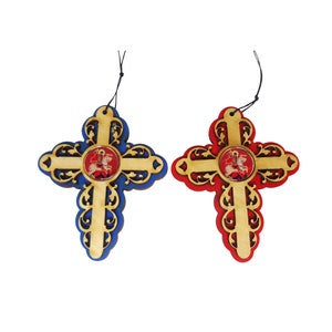 May include: Two wooden crosses with intricate designs, one blue and one red, each featuring a small round image of a saint on horseback.