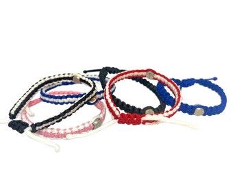 May include: Five colorful friendship bracelets with white stripes and silver beads. The bracelets are made of woven string and are tied together.