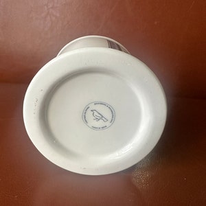May include: White ceramic mug with a black and white bird design. The mug has a black rim and a black handle. The bottom of the mug has a black circle with the text "Made in China" and a bird design. The text "Microwave & Dishwasher Safe" is also printed on the bottom of the mug.