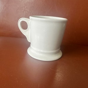 May include: White ceramic shaving mug with a handle and a wide base.