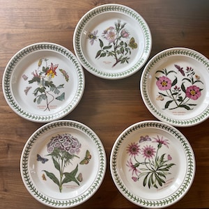 May include: Five white ceramic plates with green trim and floral designs. Each plate features a different flower and botanical illustration with the flower's name and Latin name printed on the plate.