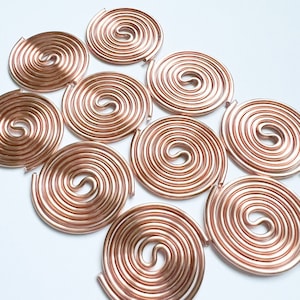 May include: Ten rose gold wire coil circles, each with a spiral design, arranged in a semi-circle pattern on a white background.
