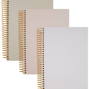 May include: Three spiral-bound notebooks in varying sizes and colors. The notebooks have gold-colored spiral bindings. The covers are in shades of beige, pink, and white. The notebooks are stacked, with the largest at the top and the smallest at the bottom.