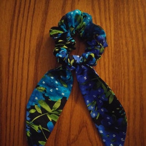 May include: A blue and green floral patterned hair scrunchie with long ties.