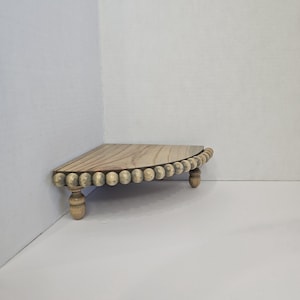 May include: A wooden corner shelf with a beaded edge and turned legs. The shelf is painted in a light gray wash.