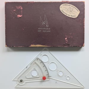 May include: A clear plastic adjustable set square with a red adjustment knob and a brown box. The box has the text "Adjustable Set Square" and a label that reads "Simplon Standard". The set square is approximately 25.4 cm in size.