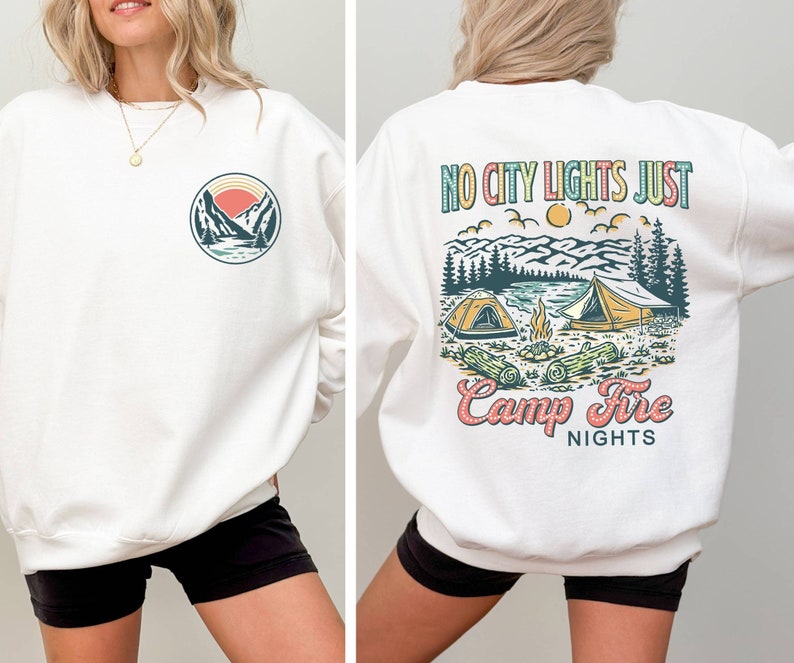 May include: White sweatshirt with a graphic of a mountain scene and the text "No City Lights Just Camp Fire Nights" on the back. The front of the sweatshirt has a smaller graphic of a mountain scene.