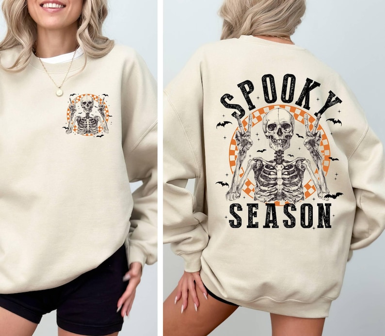 Puede incluir: Una sudadera beige con un gr&aacute;fico de esqueleto y el texto "Spooky Season" impreso en la espalda.
