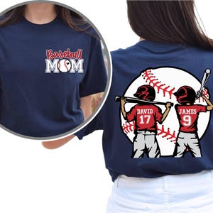 May include: Navy blue t-shirt with the text "Baseball Mom" and a baseball graphic. The back of the shirt features a graphic of two baseball players with the text "David 17" and "James 9".