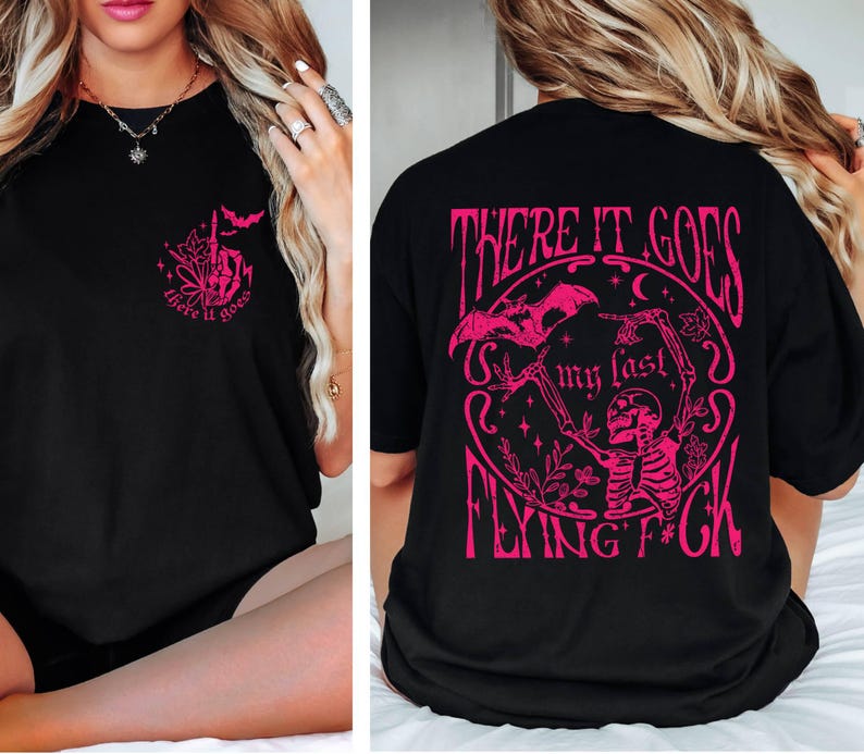 K&ouml;nnte beinhalten: Schwarzes T-Shirt mit einem rosafarbenen Grafikdruck eines Skeletts, das eine Fledermaus mit dem Text "There it goes my last flying f*ck" h&auml;lt.