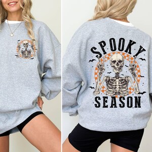 Puede incluir: Sudadera gris con un gr&aacute;fico de esqueleto y el texto "Spooky Season".