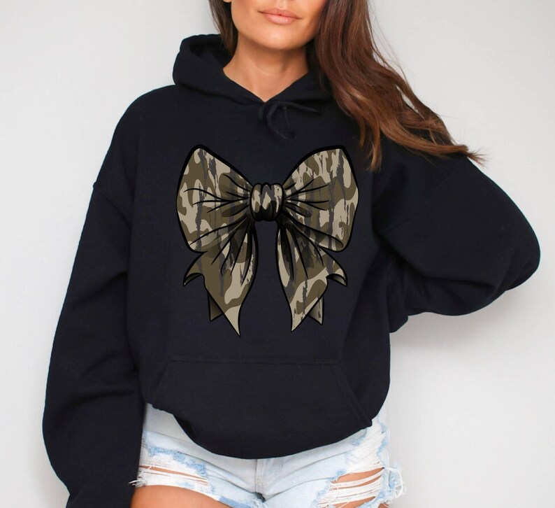 May include: Black hooded sweatshirt with a large camouflage bow design on the front.