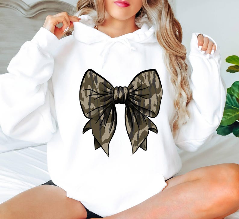 May include: White hooded sweatshirt with a large brown and white camouflage bow design on the front.