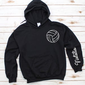 May include: Black hooded sweatshirt with a white volleyball graphic on the front and the name "Natalia" on the sleeve.