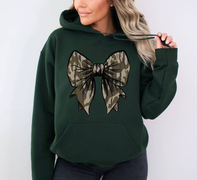 May include: A dark green hooded sweatshirt with a large camouflage bow design on the front.