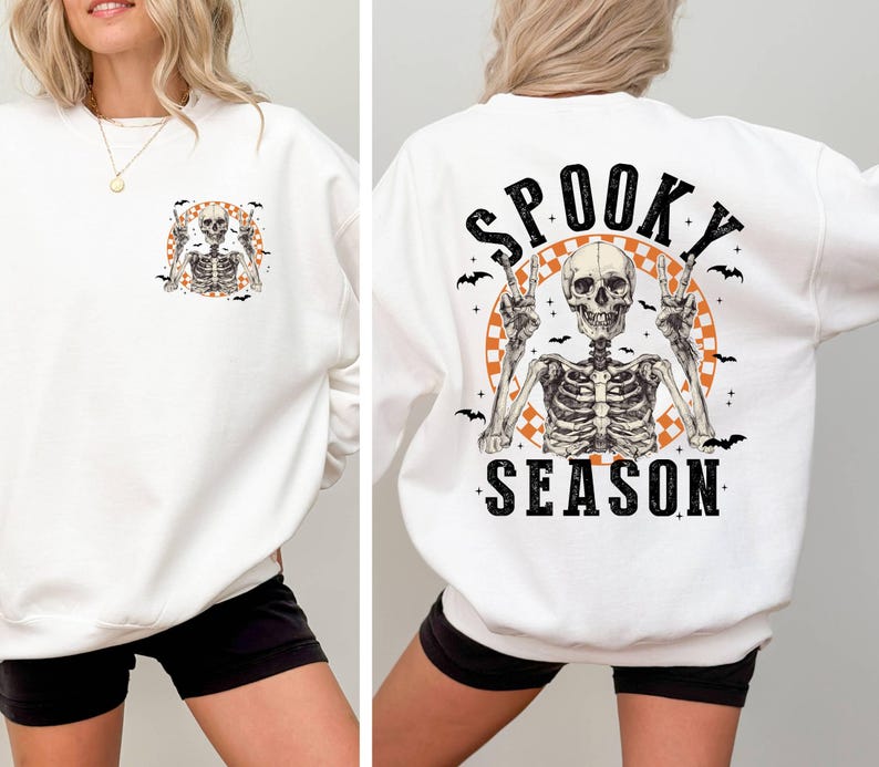 Puede incluir: Sudadera blanca con un gr&aacute;fico de esqueleto en la parte delantera y el texto "Spooky Season" con un gr&aacute;fico de esqueleto en la parte posterior.