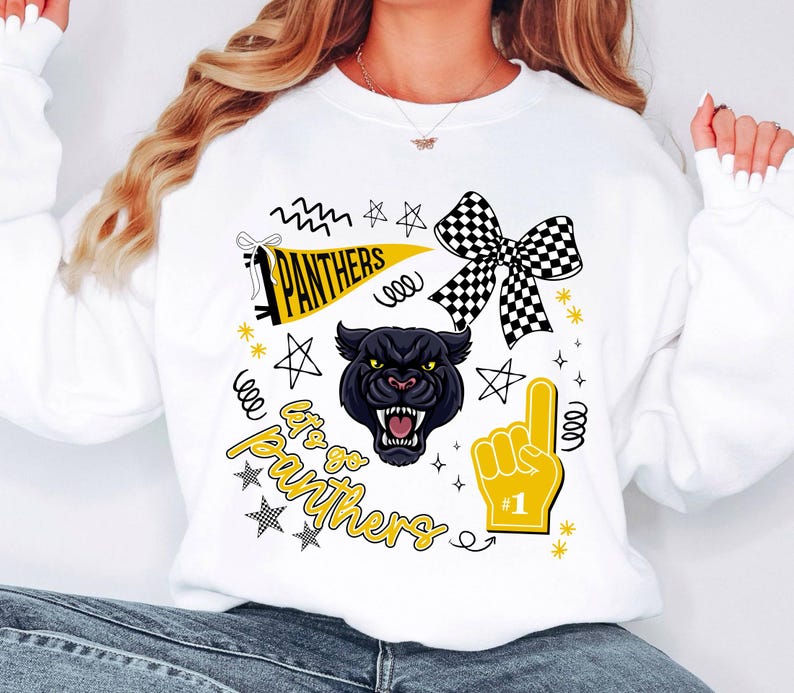 May include: White sweatshirt with a black panther graphic, a checkered bow, and the text "Let's Go Panthers." The design includes stars, a foam finger, and a pennant. The sweatshirt is a fan item.